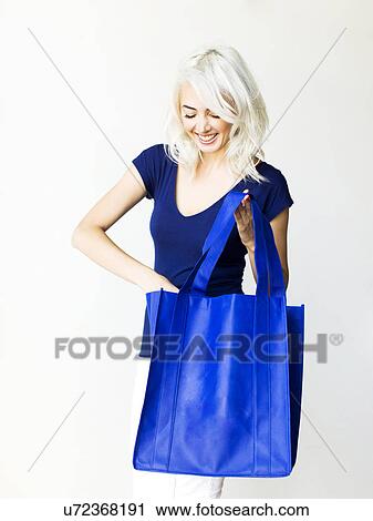 Stock Image - Studio shot of woman holding bag. Fotosearch