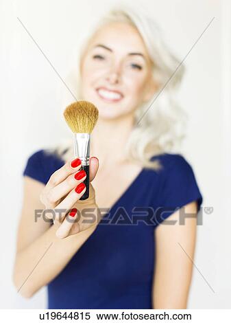 Studio shot of woman holding make-up brush View Large Photo Image Stock Photography - Studio shot of woman holding make-up brush. Fotosearch