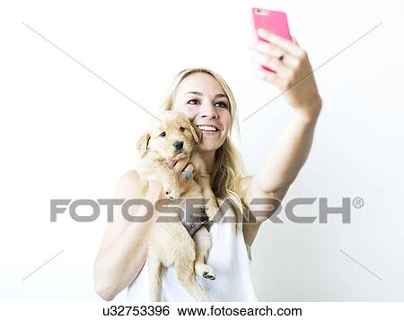 Studio shot of woman photographing self with Golden Retriever puppy View Large Photo Image Stock Photograph - Studio shot of woman photographing self with Golden Retriever puppy . Fotosearch