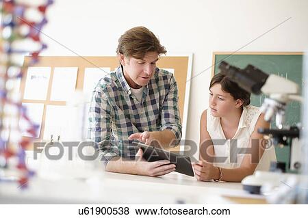 Stock Photo - Teacher talking with girl (10-11) in classroom. Fotosearch