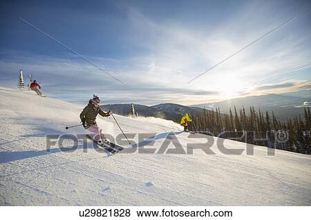 Stock Photo - Three people on ski slope at sunlight. Fotosearch