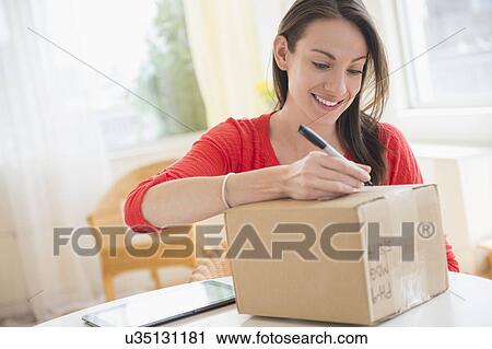 Woman addressing parcel View Large Photo Image Stock Image - Woman addressing parcel. Fotosearch