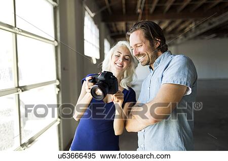 Stock Photography - Woman and man looking at pictures in digital camera. Fotosearch