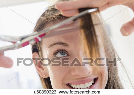 Stock Image - Woman cutting her hair. Fotosearch