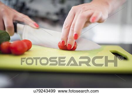 Stock Photo - Woman cutting tomatoes on cutting board. Fotosearch