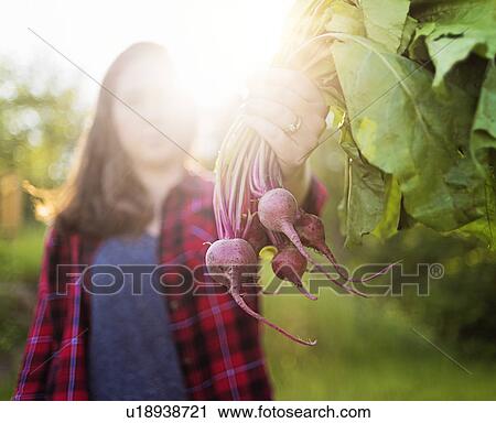 Stock Image - Woman holding bunch of radishes. Fotosearch