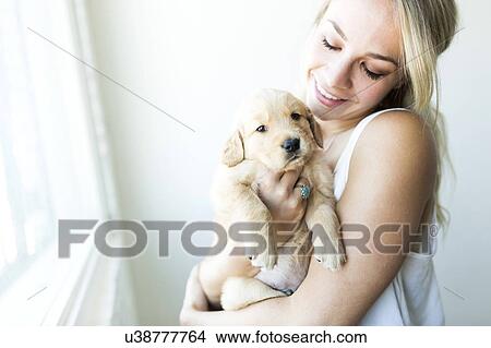 Picture - Woman holding Golden Retriever puppy . Fotosearch