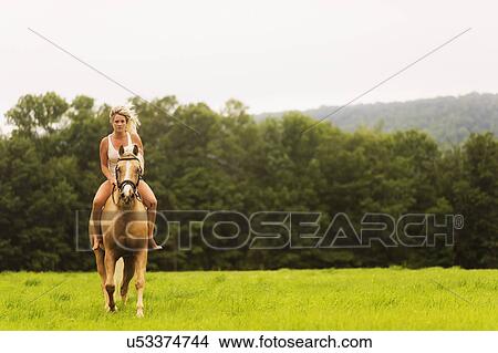 Picture - Woman horseback riding in countryside. Fotosearch