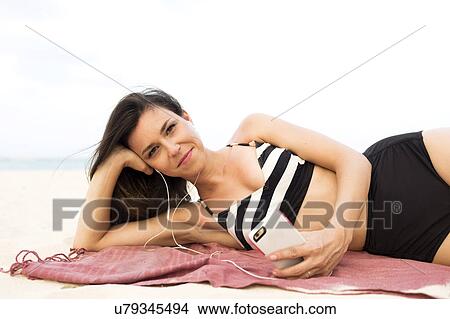 Picture - Woman in bikini relaxing on beach. Fotosearch
