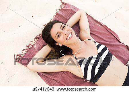 Stock Image - Woman in bikini relaxing on beach. Fotosearch