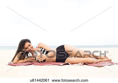 Stock Image - Woman in bikini relaxing on beach. Fotosearch