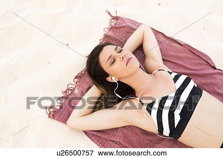 Stock Photo - Woman in bikini relaxing on beach. Fotosearch