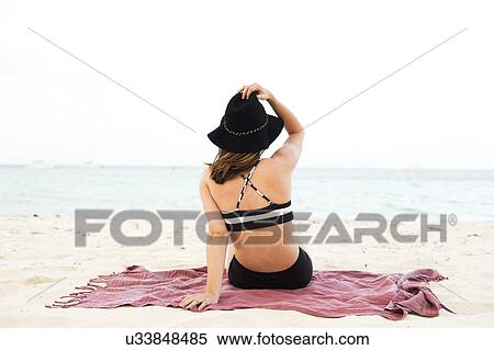 Stock Photography - Woman in bikini relaxing on beach. Fotosearch