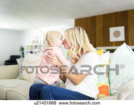 Woman kissing daughter (2-3) in living room View Large Photo Image Stock Photo - Woman kissing daughter (2-3) in living room. Fotosearch