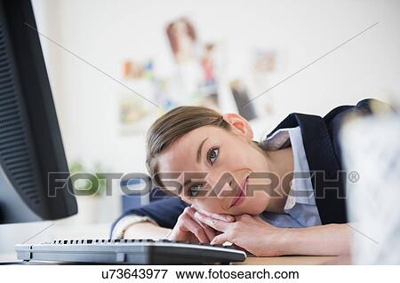 Stock Photo - Woman leaning on her desk in office. Fotosearch