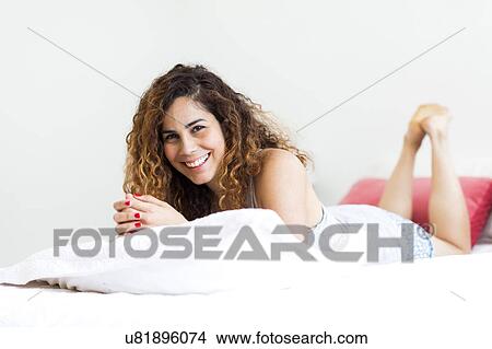 Picture - Woman lying on bed. Fotosearch