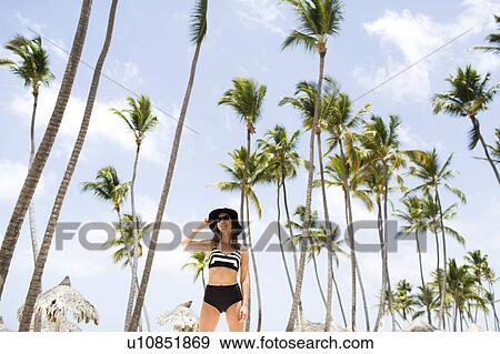 Stock Photo - Woman on beach against palm trees. Fotosearch