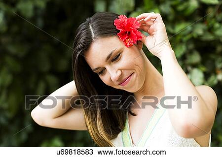 Woman putting tropical flower in her hair View Large Photo Image Stock Image - Woman putting tropical flower in her hair. Fotosearch