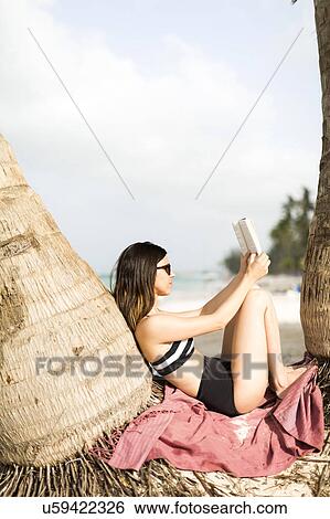 Woman relaxing by palm trees View Large Photo Image Stock Photograph - Woman relaxing by palm trees . Fotosearch