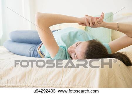 Stock Image - Woman relaxing in bed. Fotosearch