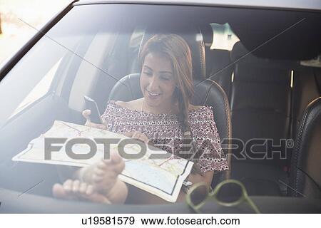 Stock Photo - woman sitting in car and looking at map. Fotosearch