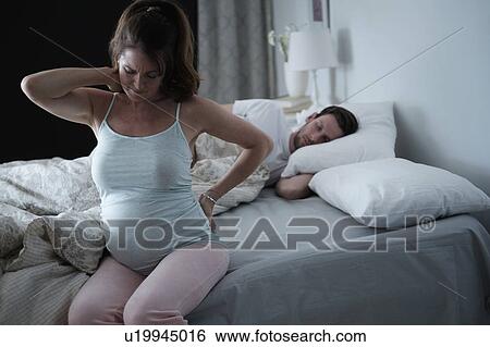 Woman sitting on bed and stretching stiff neck View Large Photo Image Stock Photograph - Woman sitting on bed and stretching stiff neck. Fotosearch