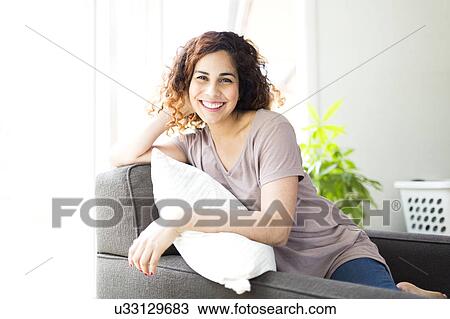 Stock Image - Woman sitting on sofa. Fotosearch