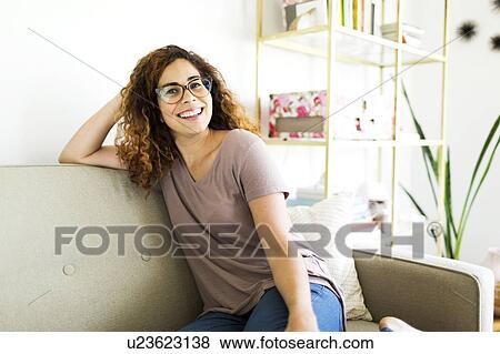 Woman sitting on sofa View Large Photo Image Stock Photo - Woman sitting on sofa. Fotosearch