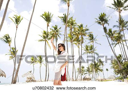 Woman standing beneath palm trees View Large Photo Image Stock Image - Woman standing beneath palm trees. Fotosearch