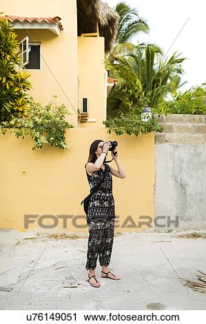 Stock Image - Woman taking photos during vacations. Fotosearch