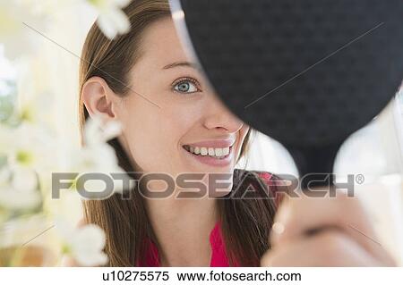 Stock Photography - Woman using hand mirror at home. Fotosearch