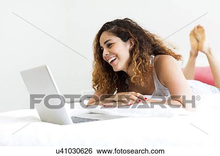 Stock Photograph - Woman using laptop in bed. Fotosearch