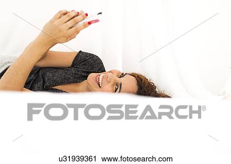 Woman using phone in bed View Large Photo Image Stock Image - Woman using phone in bed. Fotosearch