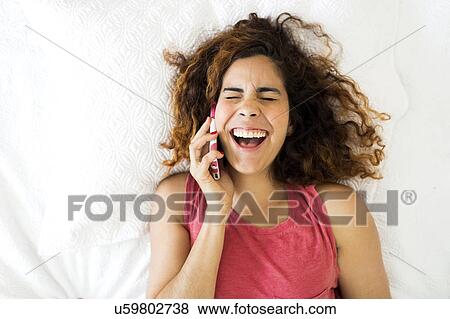 Stock Photo - Woman using phone in bed. Fotosearch