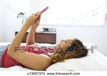 Woman using phone in bed View Large Photo Image Stock Photography - Woman using phone in bed. Fotosearch