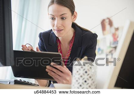 Stock Image - Woman using tablet in office. Fotosearch