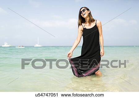 Stock Image - Woman walking on beach. Fotosearch