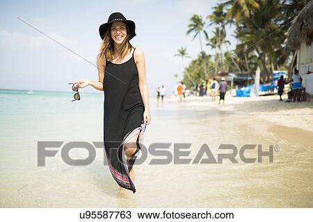 Stock Image - Woman walking on beach. Fotosearch