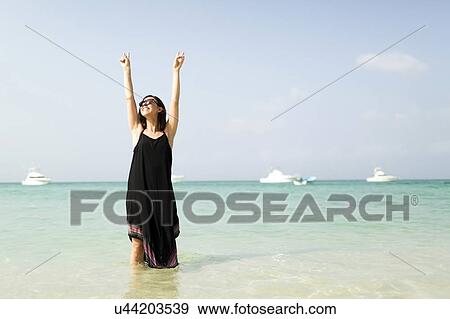 Woman with arms raised on beach View Large Photo Image Stock Photo - Woman with arms raised on beach . Fotosearch