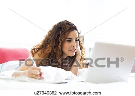 Stock Image - Woman with laptop in bed. Fotosearch