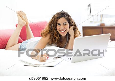 Stock Image - Woman with laptop in bed. Fotosearch