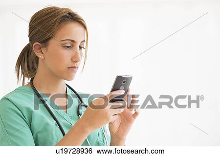 Stock Photograph - Young female doctor using smart phone. Fotosearch