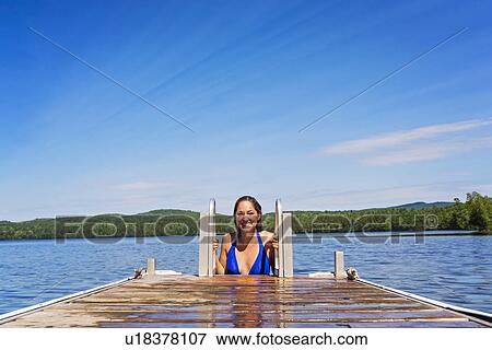 Stock Photo - Young woman coming out of water on jetty. Fotosearch