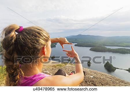 Stock Photography - Young woman framing view of lake with hands. Fotosearch