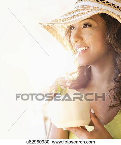 Stock Image - Young woman having drink in sunlight. Fotosearch