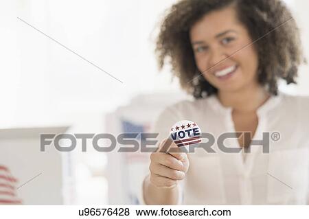 Young woman holding voting badge and smiling View Large Photo Image Stock Photo - Young woman holding voting badge and smiling. Fotosearch