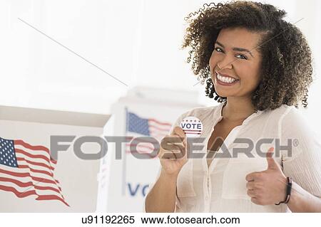 Stock Photography - Young woman holding voting badge and smiling. Fotosearch