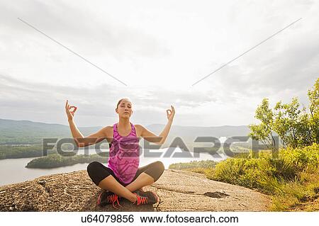 Young woman in lotus position against lake View Large Photo Image Stock Photograph - Young woman in lotus position against lake. Fotosearch