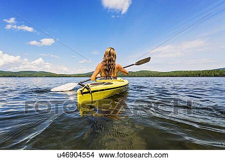 Picture - Young woman kayaking on lake. Fotosearch