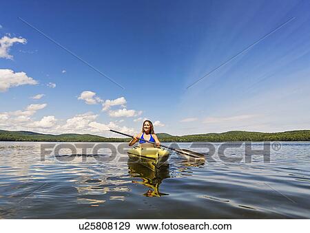Stock Photo - Young woman kayaking on lake. Fotosearch